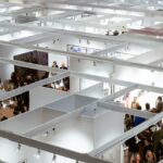 Aerial view of a crowded art exhibition in Paris with visitors in indoor galleries.