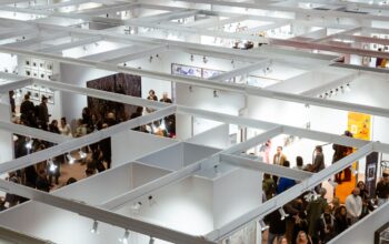 Aerial view of a crowded art exhibition in Paris with visitors in indoor galleries.