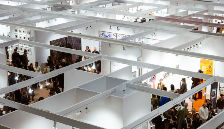 Aerial view of a crowded art exhibition in Paris with visitors in indoor galleries.